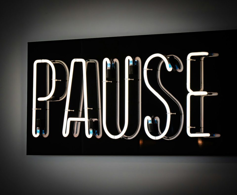 White neon sign spelling the word pause